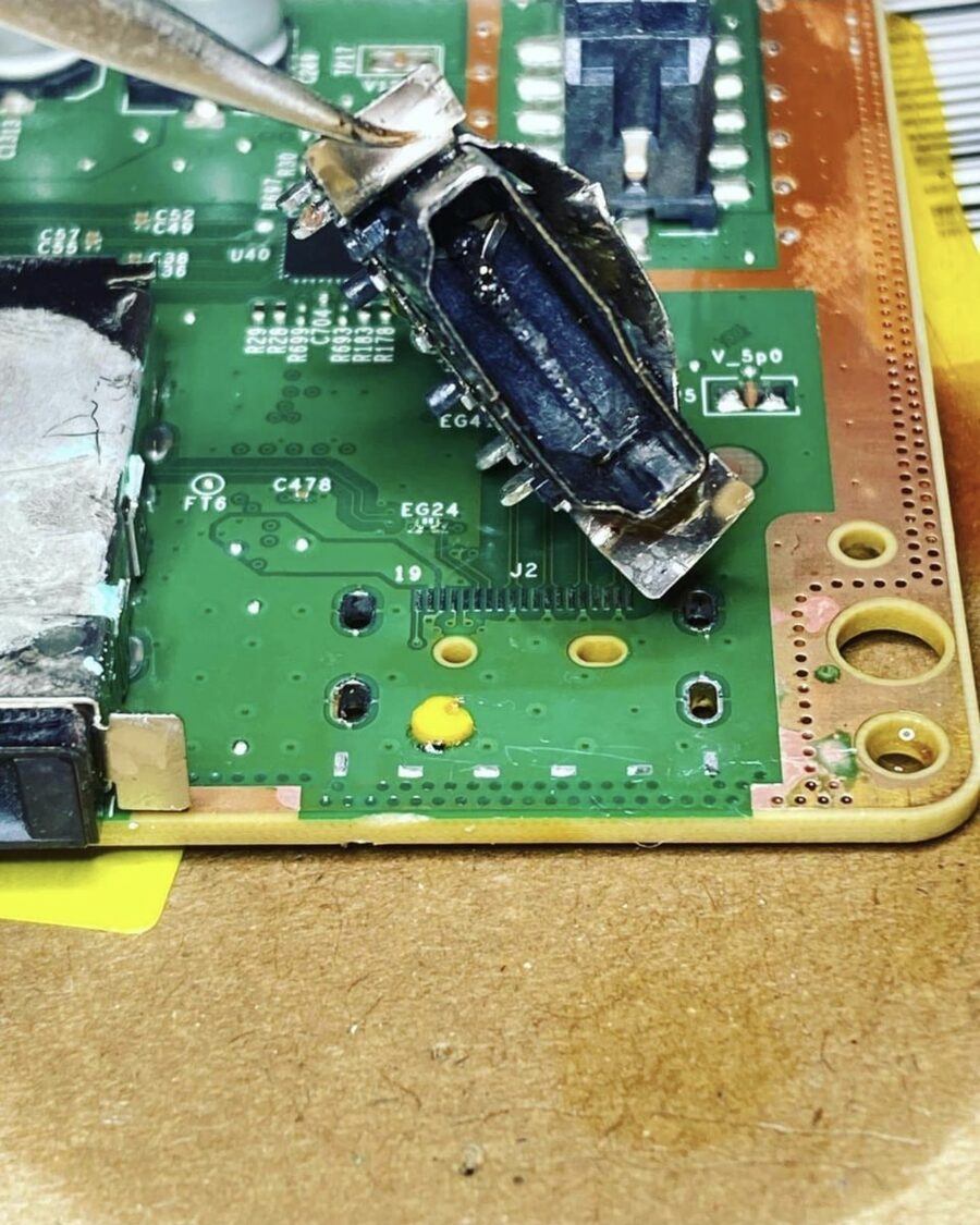 Close-up of a PS5 HDMI port being repaired under microscope